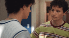 two young men are looking at each other in a room