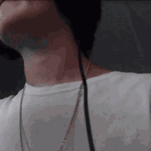 a man wearing headphones and a necklace looks down at something