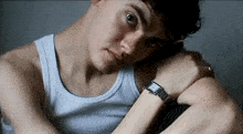 a man wearing a white tank top and a watch on his wrist