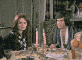 a man and a woman sit at a table with plates of food and wine glasses
