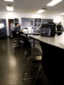 a man sits at a table in front of a pepsi machine