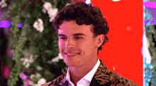 a man with curly hair is wearing a black and gold jacket