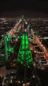 a city at night with a green tower in the center