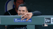a man leaning over a rockies.com sign