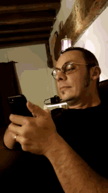 a man wearing glasses is looking at a cell phone