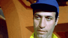 a close up of a man wearing a blue hat and a yellow shirt