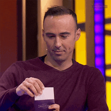 a man in a maroon sweater is holding a piece of paper that says passwo