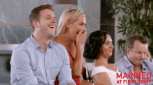 a man and a woman are laughing while sitting next to each other .