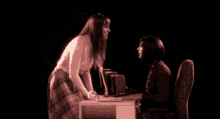 a woman in a plaid skirt is standing in front of a desk