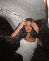 a woman in a white tank top is sitting in a car