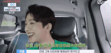 a man in a green shirt is smiling in a car with chinese writing on it