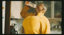 a man in a yellow sweater drinks from a hershey 's bottle