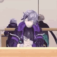 a man with purple hair is sitting at a table with his eyes closed and holding a knife .