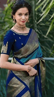 a woman wearing a blue blouse and a blue and gold saree