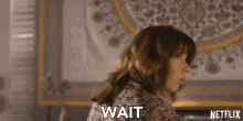 a woman with a surprised look on her face and the word wait below her