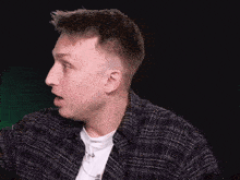 a man in a plaid shirt is making a surprised face with his mouth open