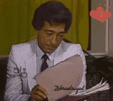 a man in a suit and tie is reading a piece of paper