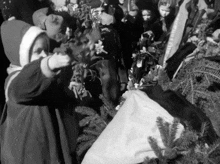 a black and white photo of a girl holding a plant with a sign in the background that says merry christmas