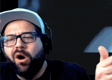a man with a beard wearing glasses and headphones is giving a thumbs up