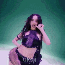a woman in a purple fur crop top and shorts is eating a piece of food .