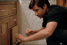 a man in a black shirt is opening a drawer in a bathroom