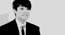 a young man in a suit and tie is making a funny face in a black and white photo .