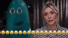 a woman is standing in front of a blue ghost with smiley faces on it .