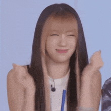 a woman with long hair is clapping her hands in the air .