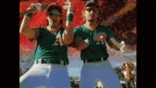 two baseball players wearing a green jersey with the letter a on it