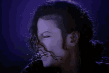 a close up of a man 's face with his eyes closed and his hair blowing in the wind