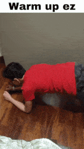 a man in a red shirt is doing push ups on a wood floor
