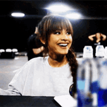 a woman is smiling while sitting at a table with bottles of water
