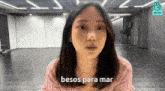 a woman in a pink sweater says " besos para mar " in spanish