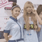 two girls are standing next to each other and one of them is holding the other 's arm .