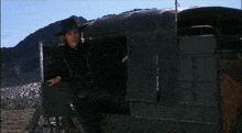 a man in a cowboy hat is standing next to a wagon