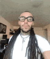a man with dreadlocks and glasses is wearing a white shirt .