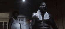a man with a towel around his neck is standing next to another man in a dark room .