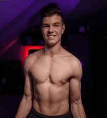 a young man without a shirt is smiling in front of a purple light