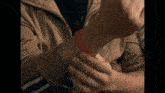 a person wearing a brown jacket has a red bracelet around their wrist
