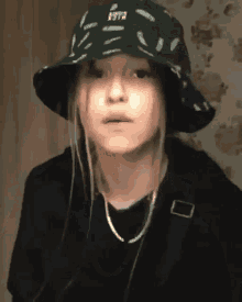 a young girl wearing a bucket hat and a black shirt looks at the camera .
