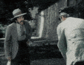 a man in a suit and hat is talking to another man