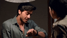 a man in a green shirt looks at his watch