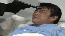 a man laying in a hospital bed with a gun pointing to his forehead