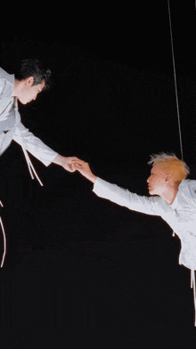 two men are reaching for each other 's hands in a dark room