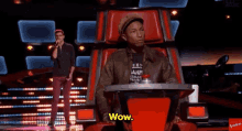 a man sitting in a chair with the word wow on his shirt
