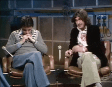 two men are sitting next to each other in front of microphones