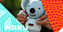 a person is holding a crocheted koala bear with the word waru in the corner