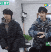 two young men are standing next to each other in a room with a sign that says ' 金典 ' on it
