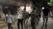 a group of young men are walking down a street at night