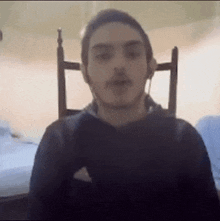 a man wearing headphones is sitting in a chair and looking at the camera .